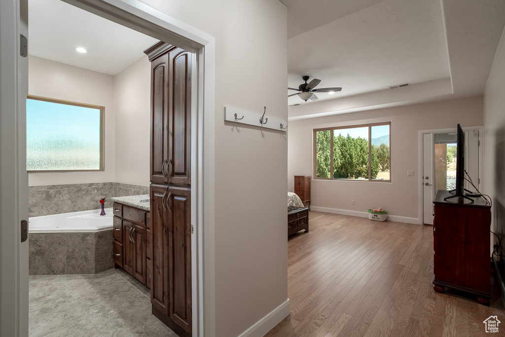 Bathroom featuring a garden tub, a ceiling fan, vanity, wood finished floors, and baseboards