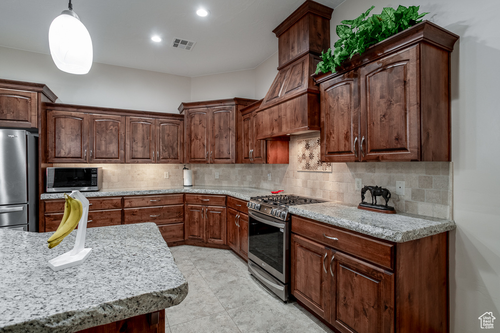 Kitchen with stainless steel appliances, tasteful backsplash, pendant lighting, recessed lighting, and light stone countertops