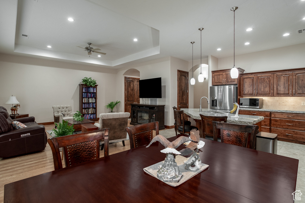 Dining room with a ceiling fan, recessed lighting, a tray ceiling, arched walkways, and baseboards