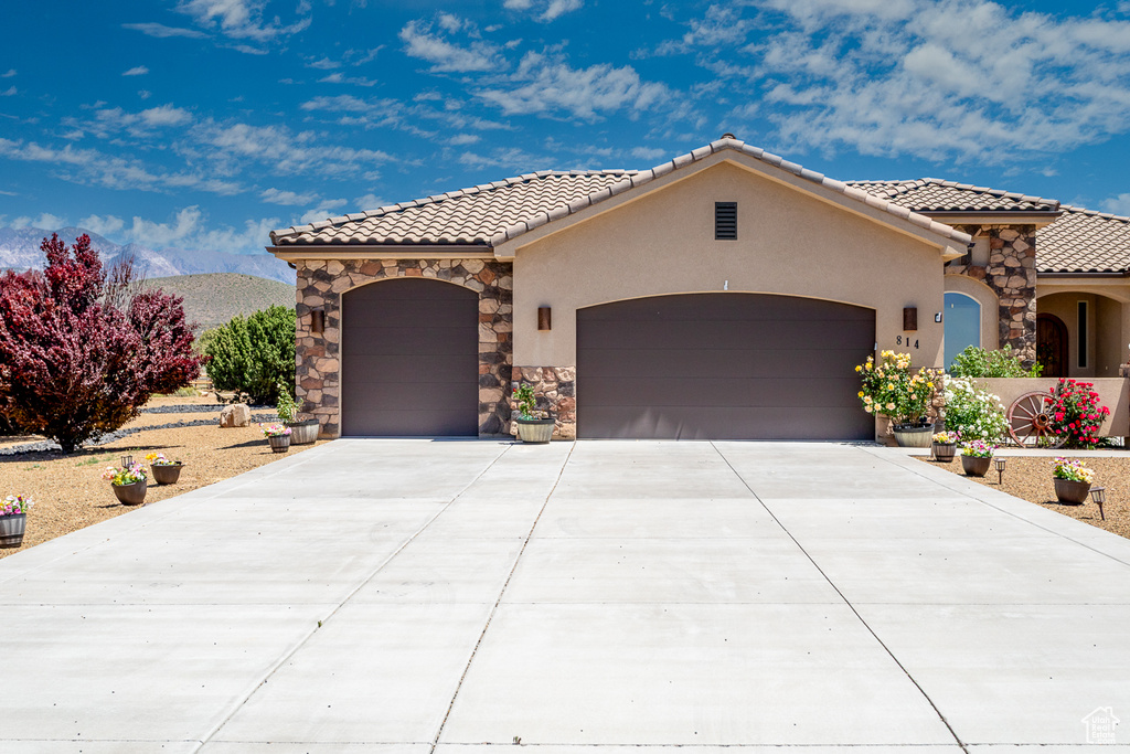 Mediterranean / spanish-style home featuring a tile roof, a garage, stucco siding, and concrete driveway