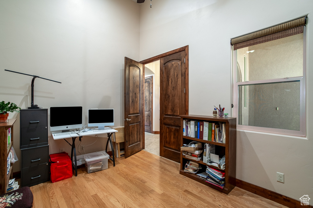 Office featuring light wood-type flooring, baseboards, and a high ceiling