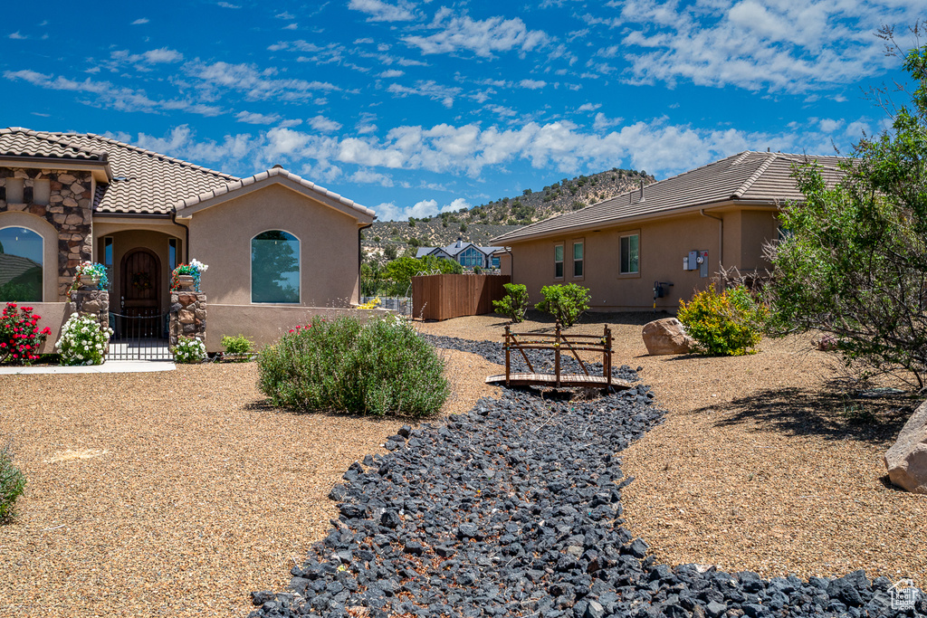 View of home\'s exterior featuring a tile roof, stucco siding, and a gate