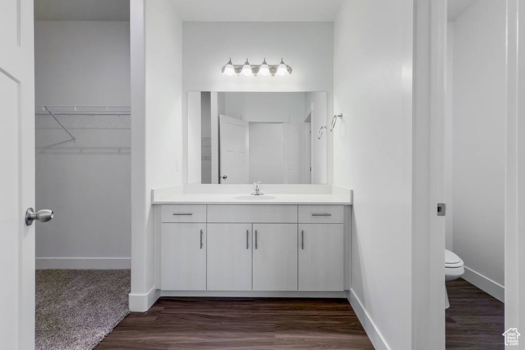 Bathroom with vanity, toilet, wood finished floors, and baseboards