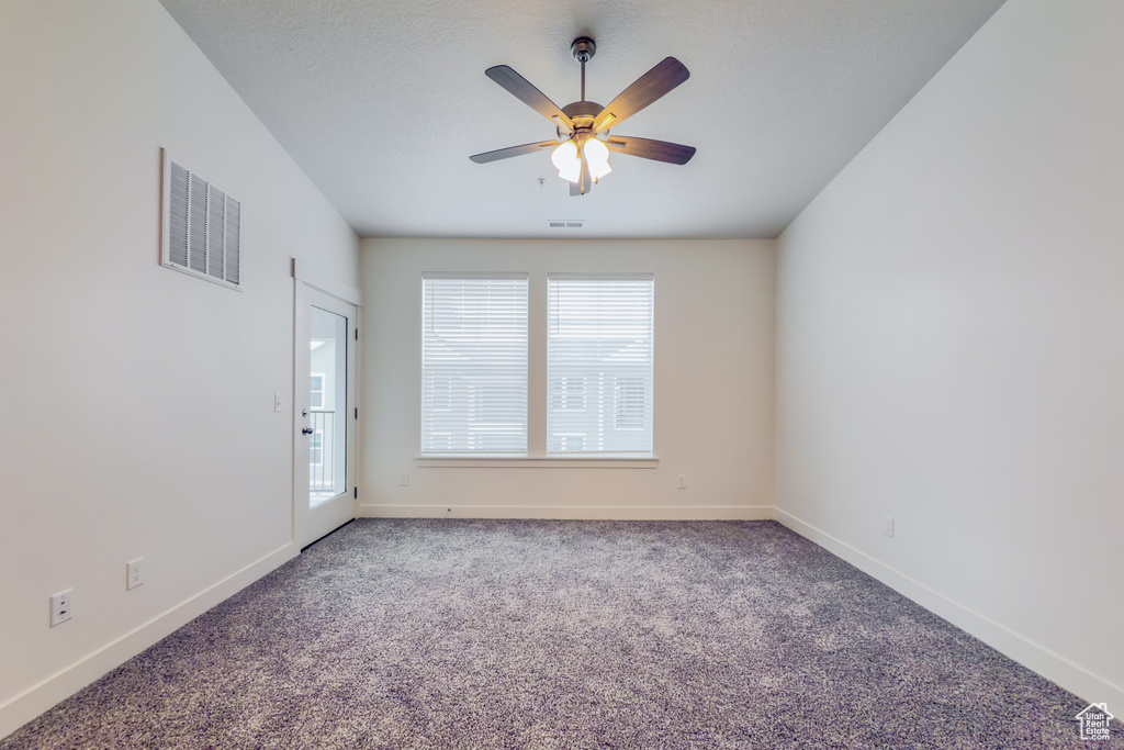 Carpeted spare room with ceiling fan and baseboards