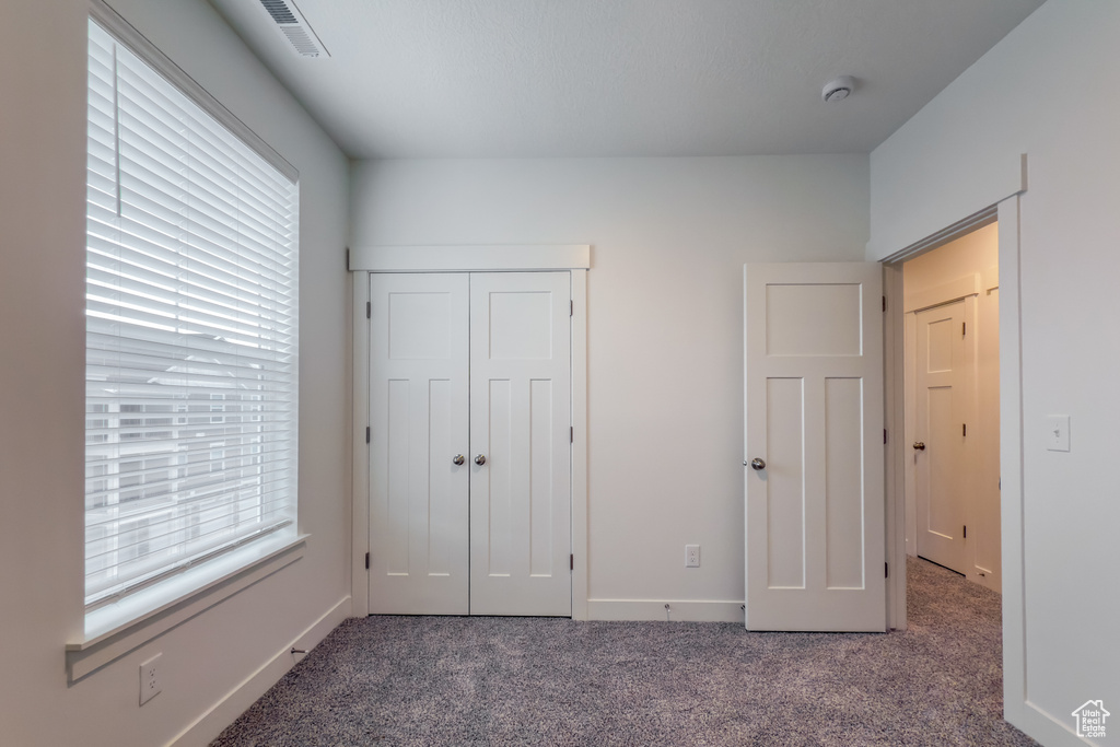 Unfurnished bedroom with carpet, a closet, and baseboards