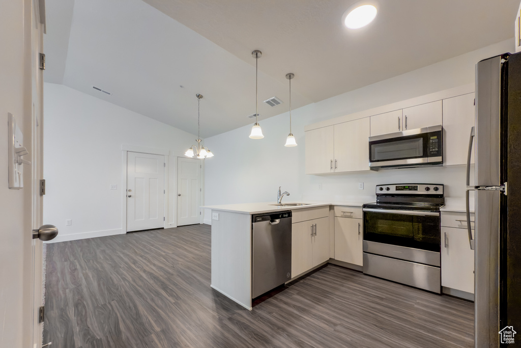 Kitchen with stainless steel appliances, a peninsula, a sink, dark wood-style flooring, and lofted ceiling