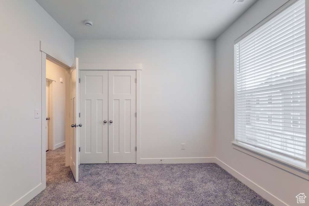 Unfurnished bedroom featuring carpet, a closet, and baseboards