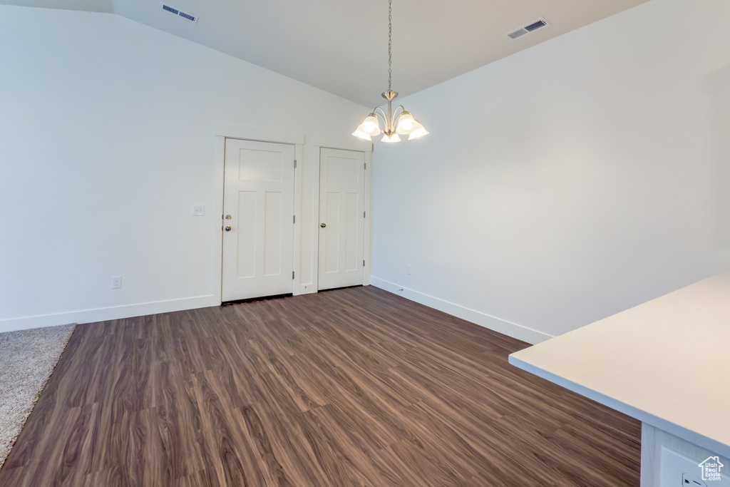 Unfurnished dining area featuring a chandelier, vaulted ceiling, baseboards, and dark wood finished floors