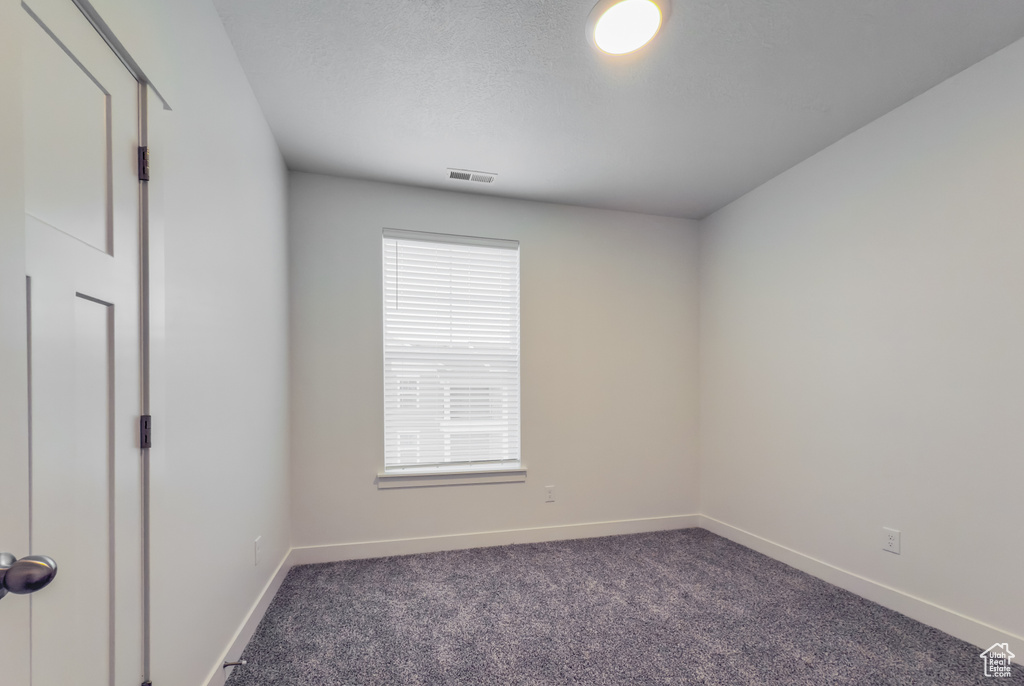 Unfurnished room with dark carpet and baseboards