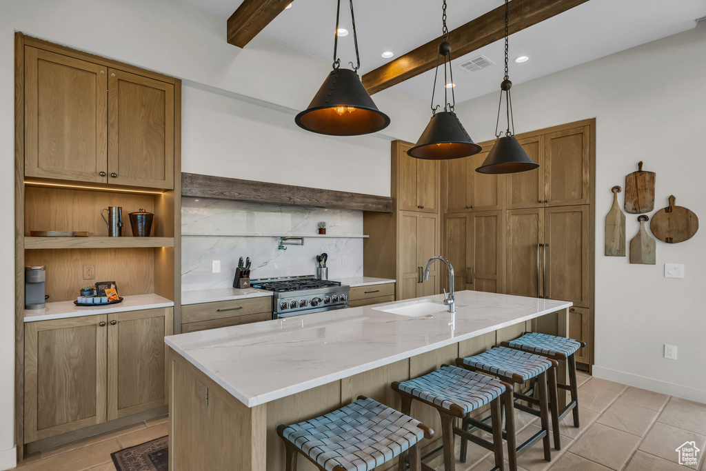 Kitchen featuring a sink, gas stove, beamed ceiling, tasteful backsplash, and a breakfast bar area