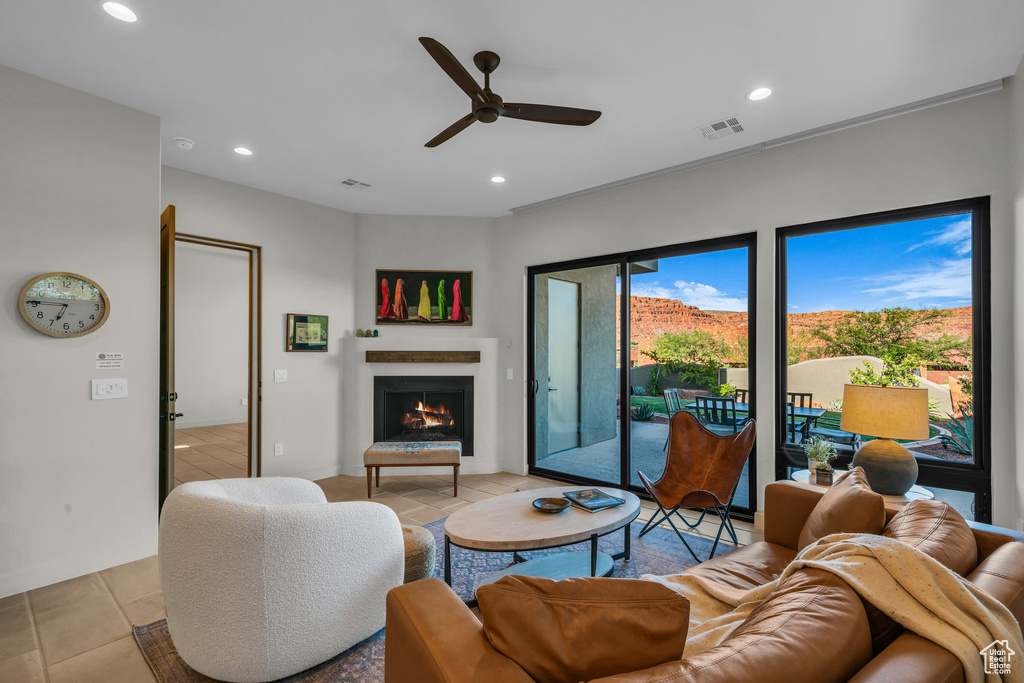 Living area featuring a ceiling fan, a lit fireplace, and recessed lighting