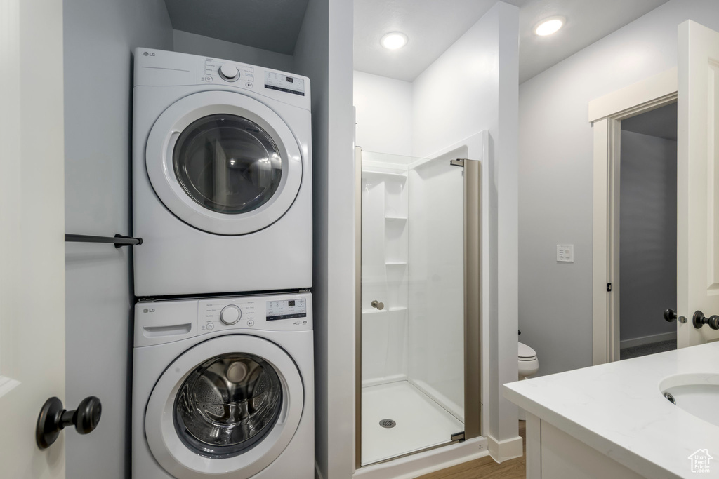 Bathroom with stacked washing machine and dryer, a shower stall, vanity, and wood finished floors