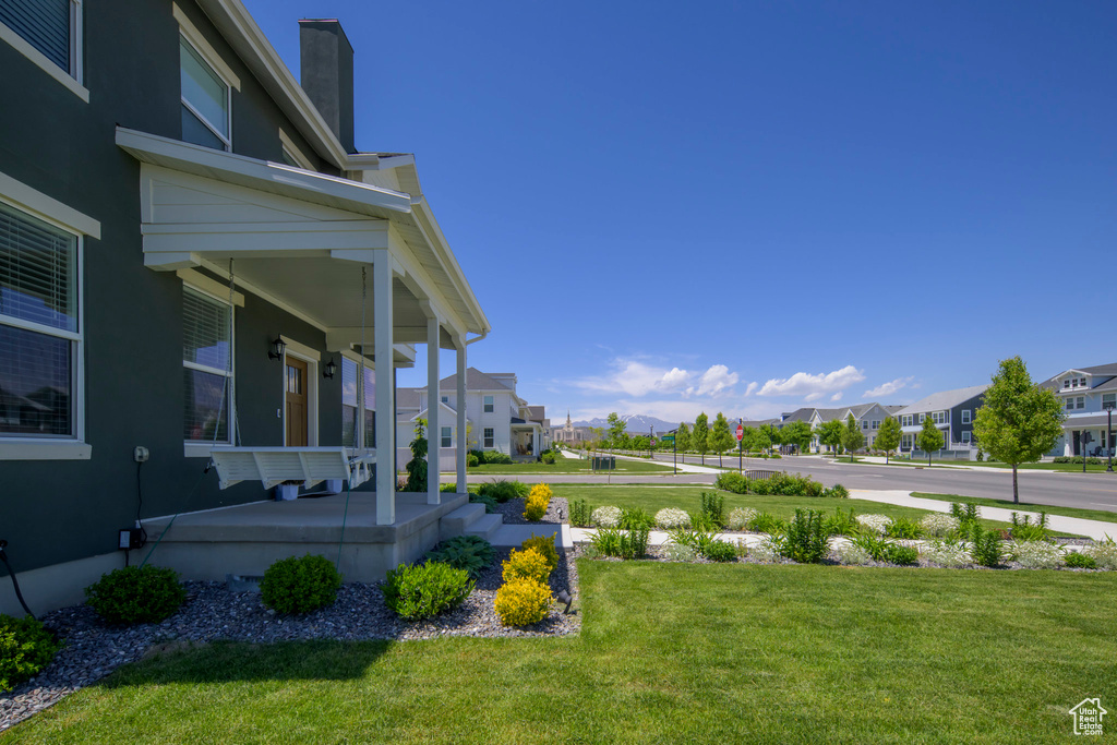 View of green lawn featuring a porch and a residential view
