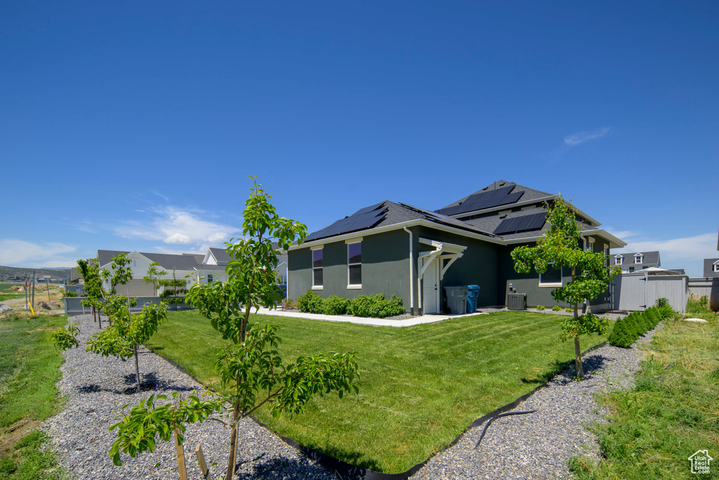 Rear view of house featuring stucco siding and solar panels