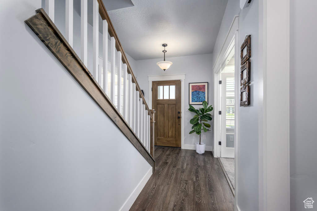 Entryway featuring dark wood-style flooring, baseboards, and stairway