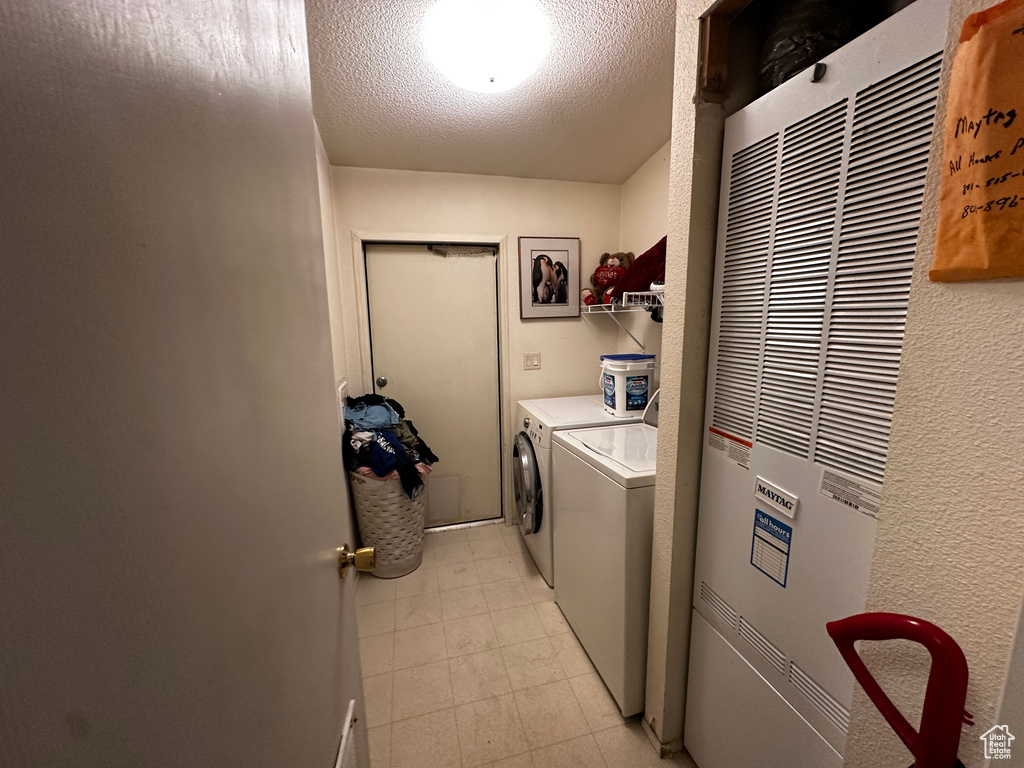 Washroom featuring a heating unit, washer and clothes dryer, and a textured ceiling