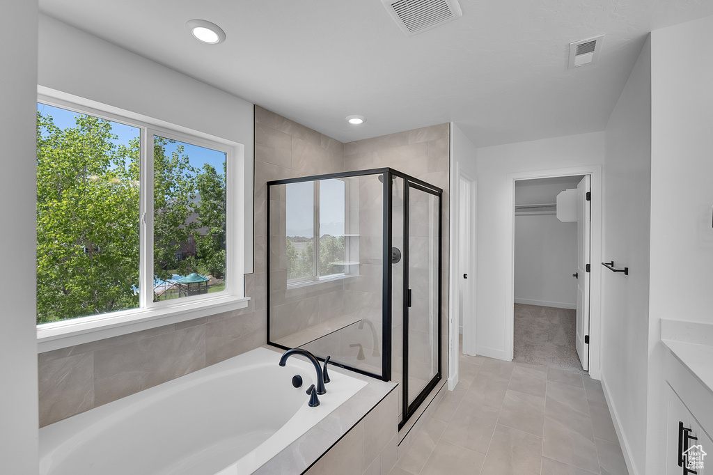 Bathroom featuring a shower stall, a garden tub, tile patterned floors, baseboards, and recessed lighting