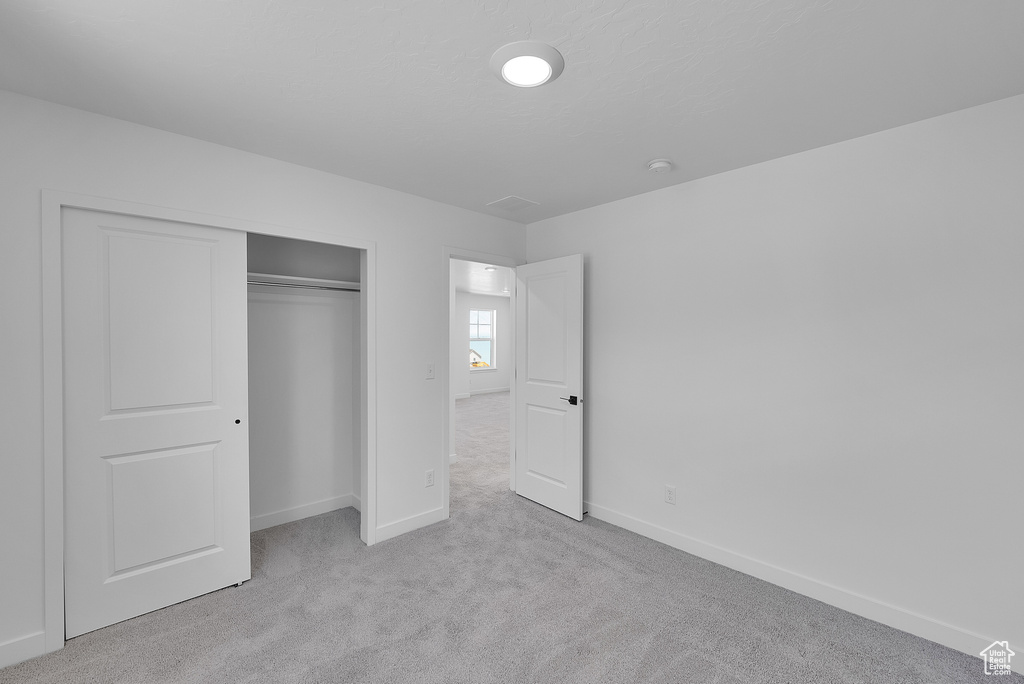 Unfurnished bedroom featuring carpet floors, baseboards, and a closet