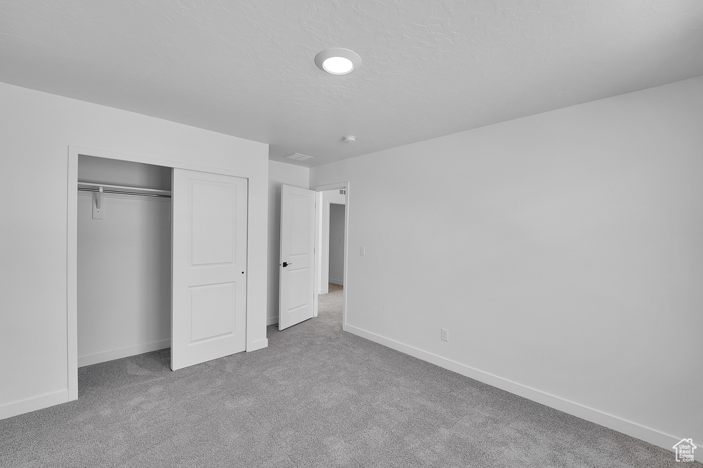 Unfurnished bedroom featuring carpet floors, baseboards, and a closet