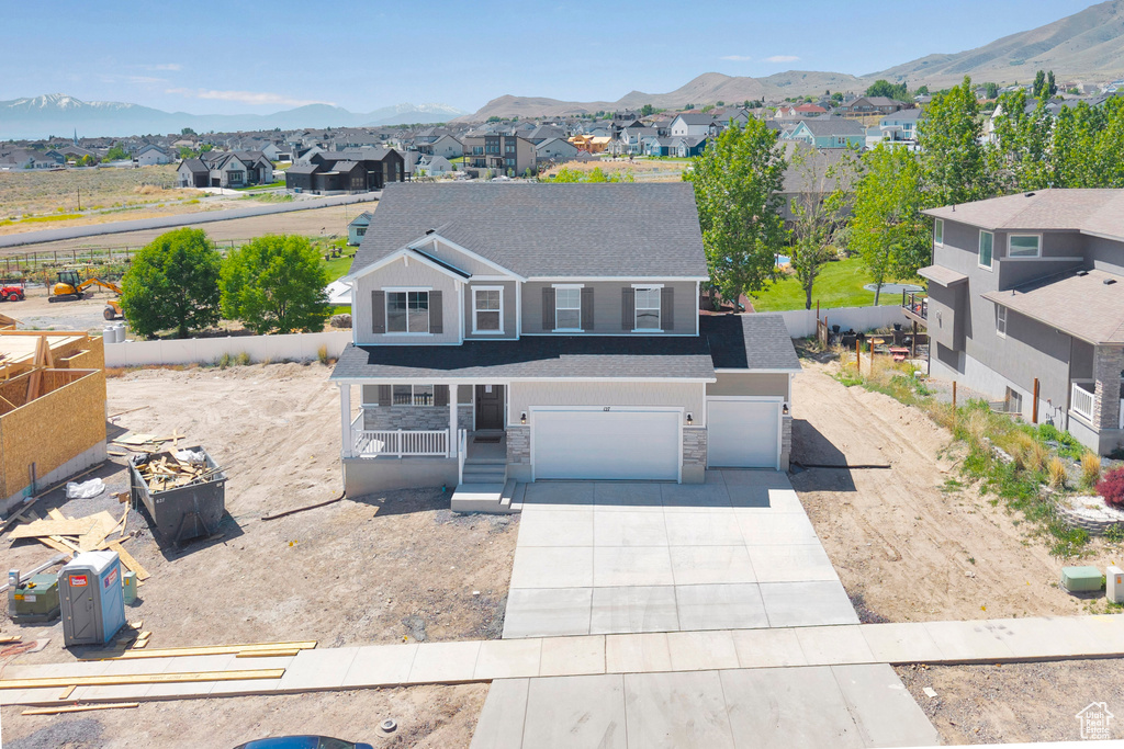 Traditional-style home with a residential view, covered porch, driveway, an attached garage, and a mountain view