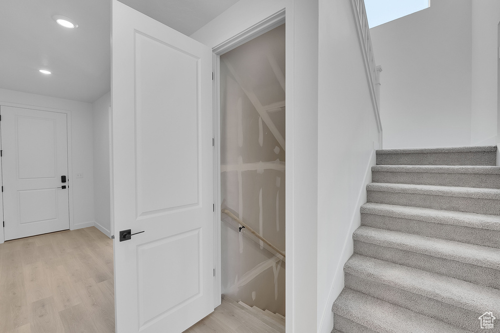 Staircase with wood finished floors and recessed lighting