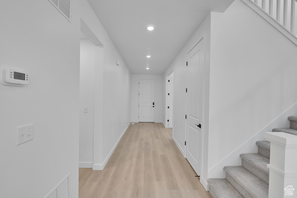 Hallway with light wood-type flooring, recessed lighting, stairs, and baseboards