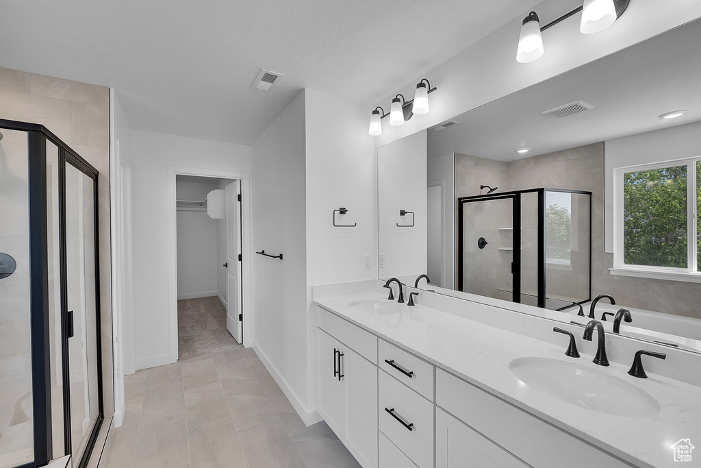 Bathroom featuring a shower stall, double vanity, and baseboards