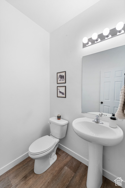 Bathroom featuring wood finished floors, baseboards, toilet, and a sink
