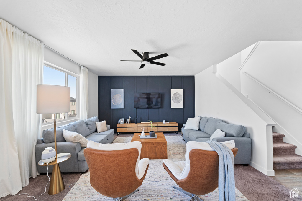 Living area featuring ceiling fan, stairway, and baseboards