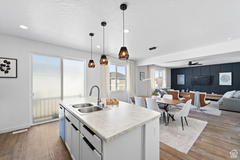 Kitchen with a sink, open floor plan, a ceiling fan, light wood finished floors, and light countertops