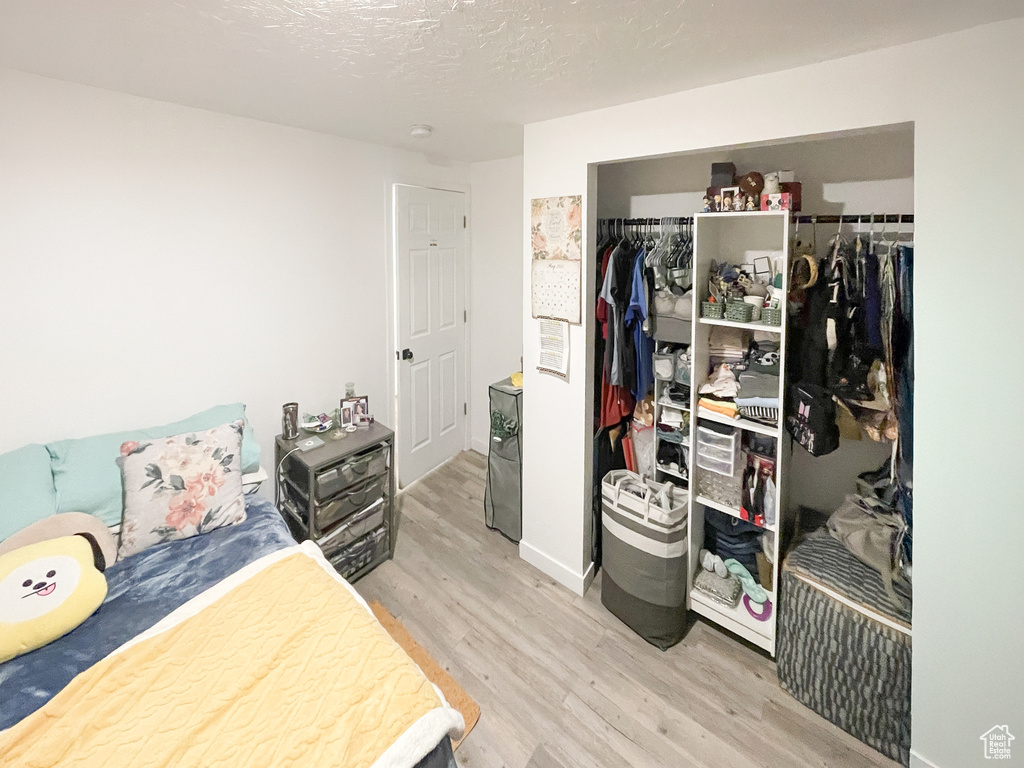 Bedroom featuring light wood finished floors, a closet, and a textured ceiling