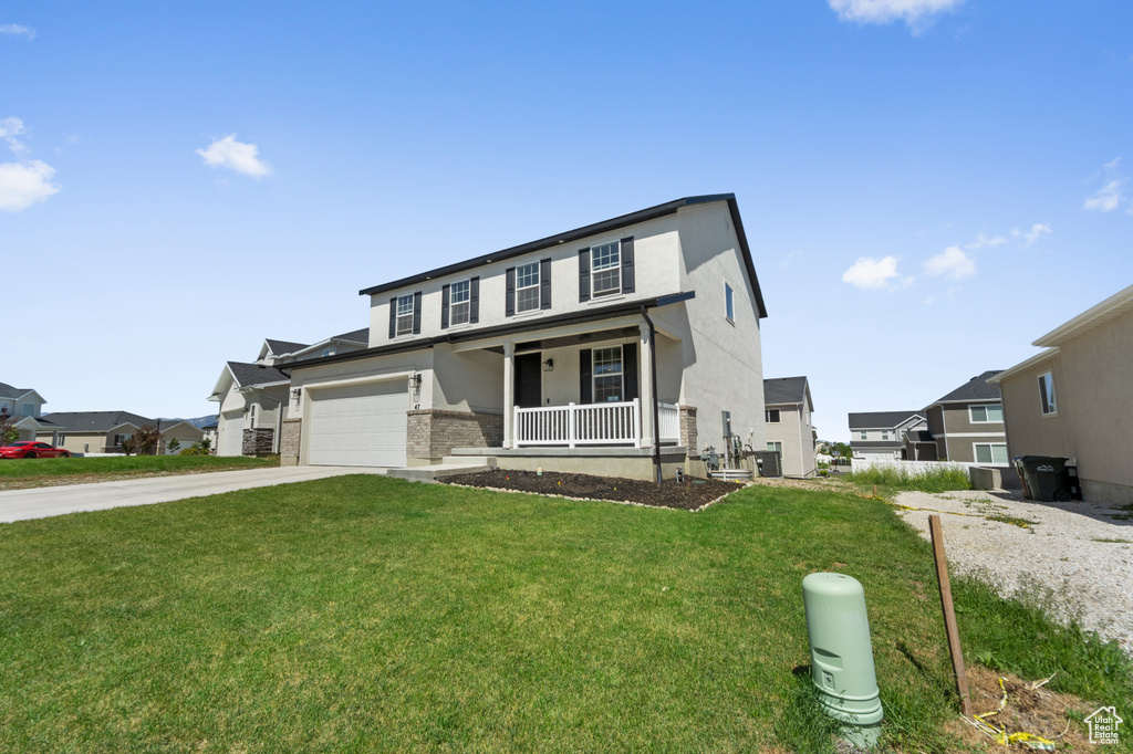 View of front facade featuring covered porch, driveway, a front yard, stucco siding, and cooling unit