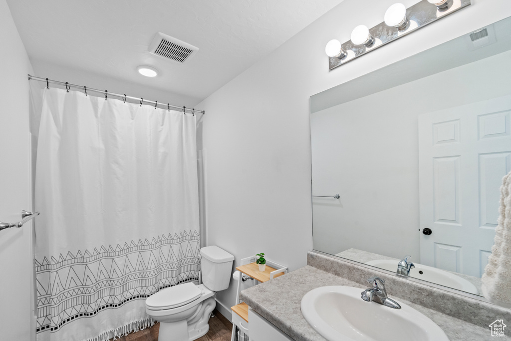 Full bathroom featuring wood finished floors, vanity, toilet, and a shower with shower curtain