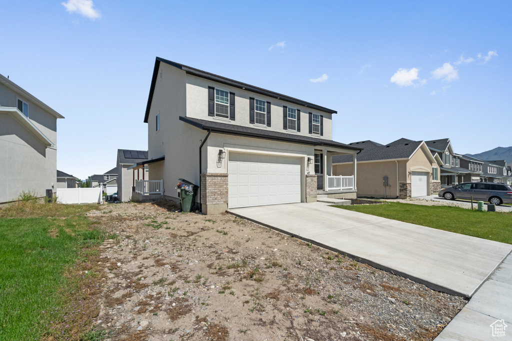 View of front facade featuring concrete driveway, an attached garage, a residential view, stucco siding, and a porch
