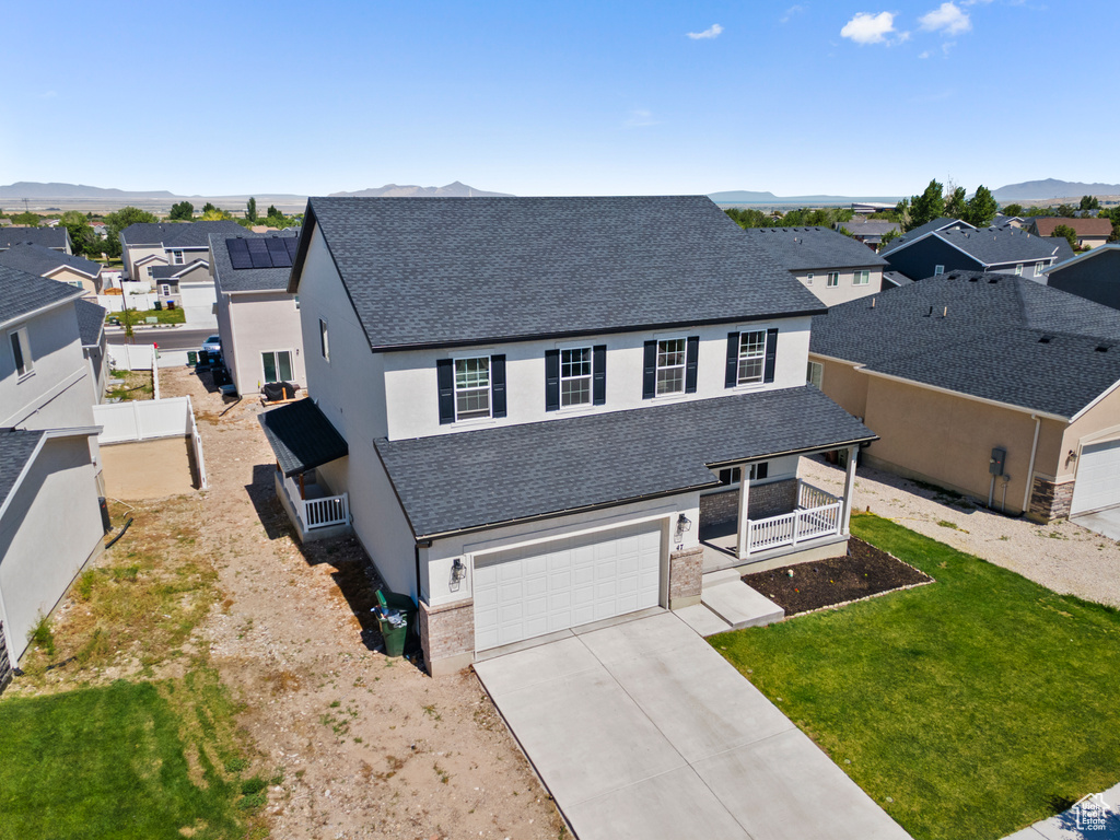 View of front facade with a residential view, roof with shingles, a porch, driveway, and stucco siding