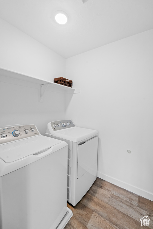 Laundry area featuring washer and dryer, light wood-style floors, and baseboards