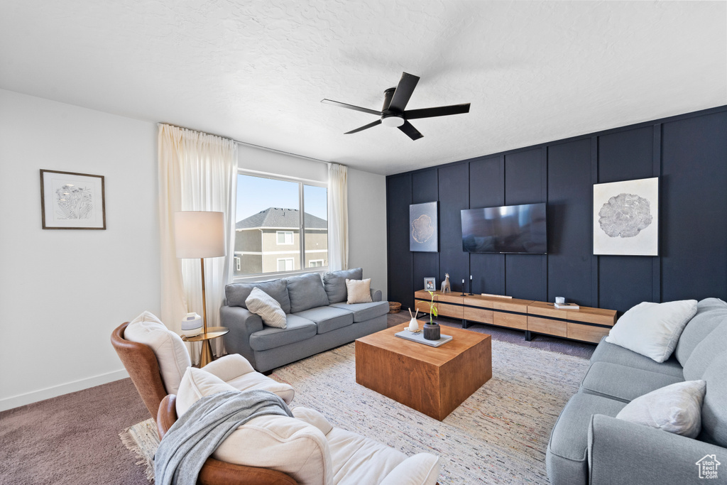 Carpeted living area with ceiling fan and baseboards