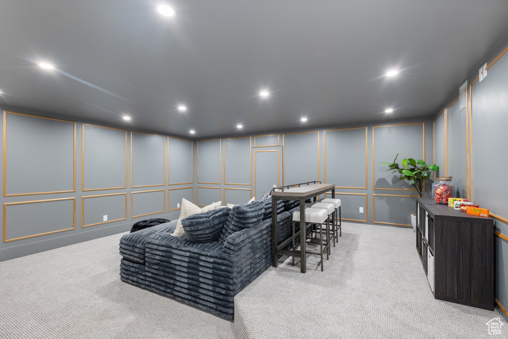 Living area with a decorative wall, carpet flooring, and recessed lighting
