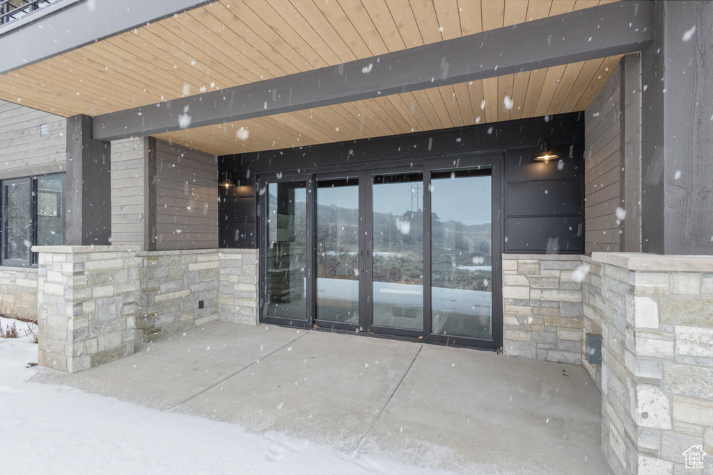 Property entrance featuring stone siding and a patio