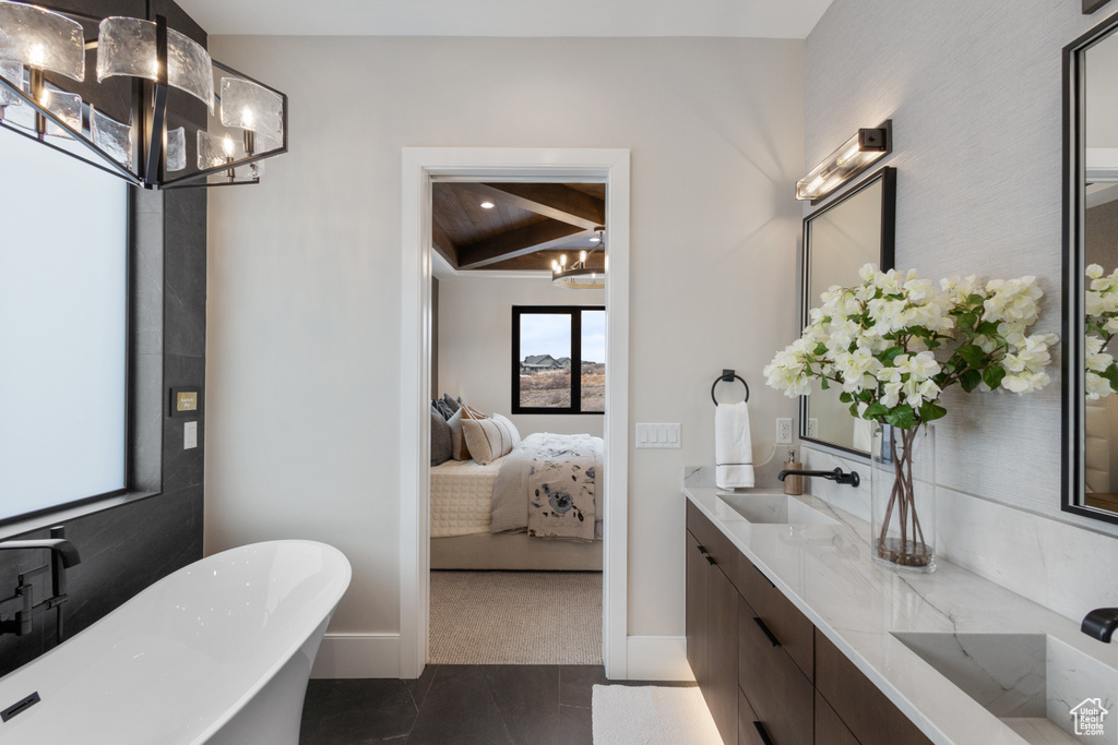 Ensuite bathroom with a chandelier, a freestanding tub, double vanity, and baseboards