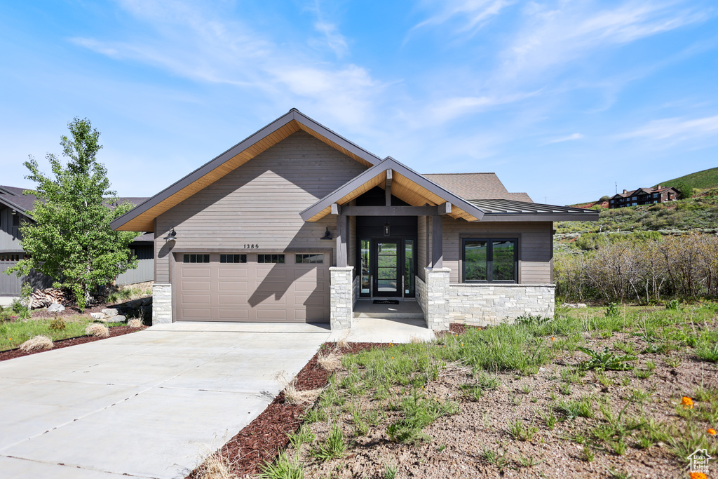 View of front of home featuring a garage, stone siding, and concrete driveway