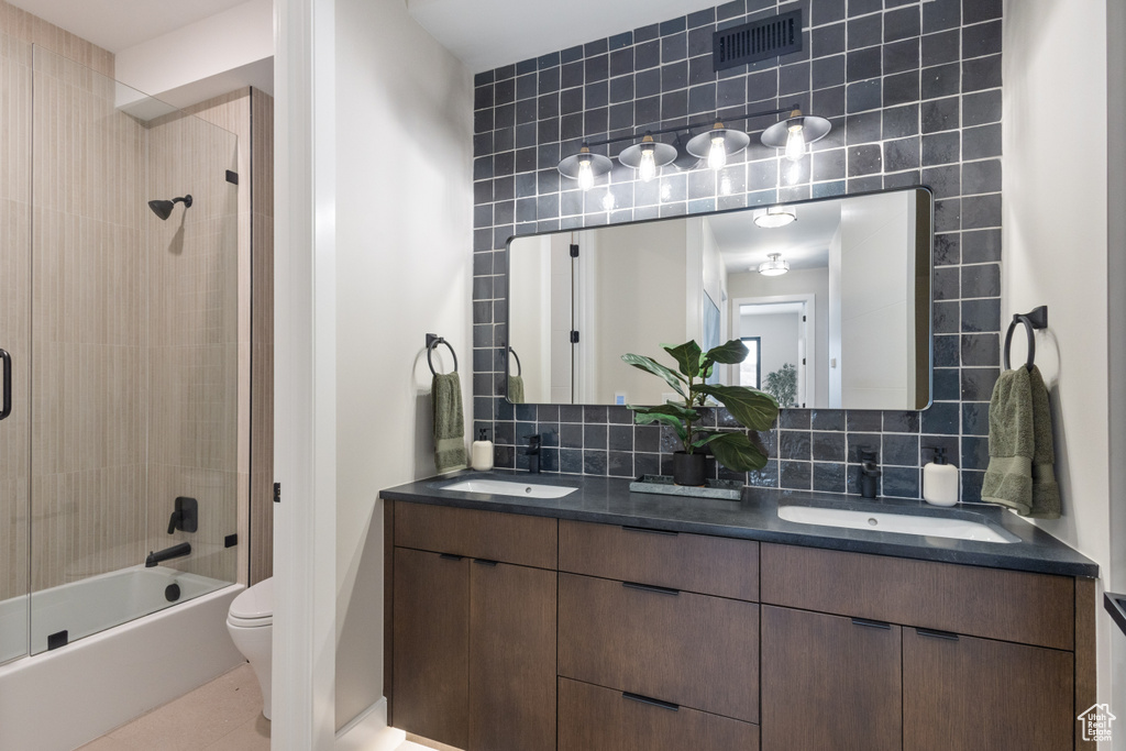 Bathroom with toilet, double vanity, shower / washtub combination, backsplash, and tile patterned floors