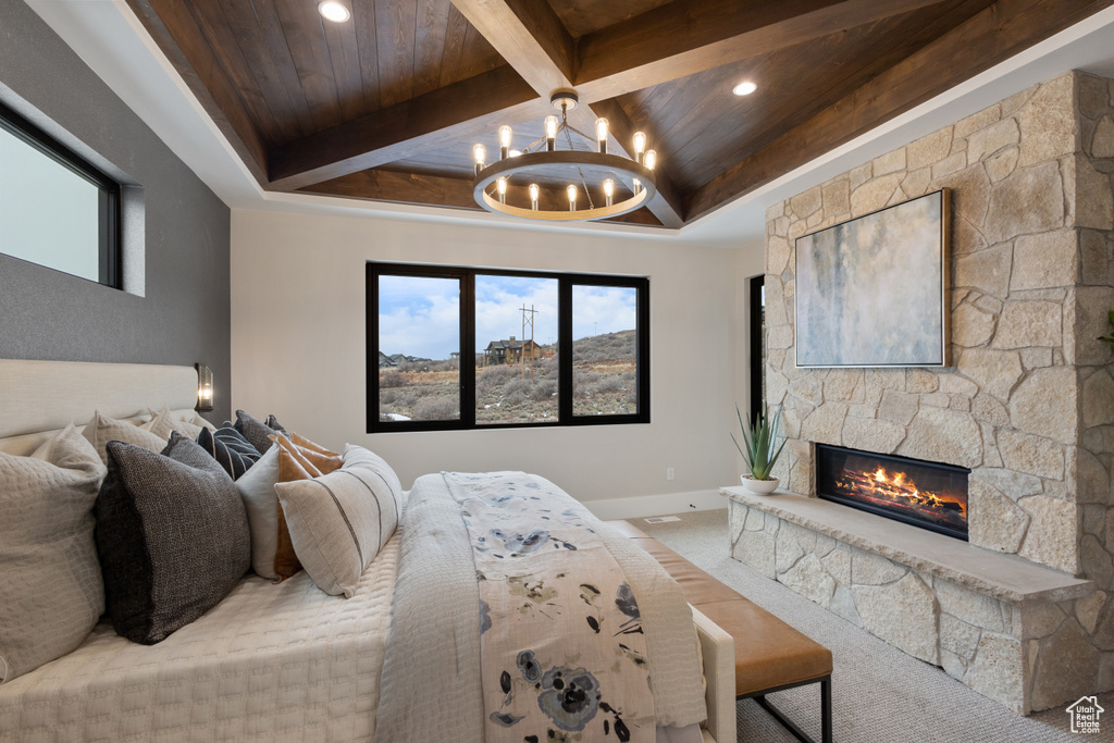 Carpeted bedroom with wood ceiling with exposed beams, a chandelier, baseboards, a stone fireplace, and coffered ceiling