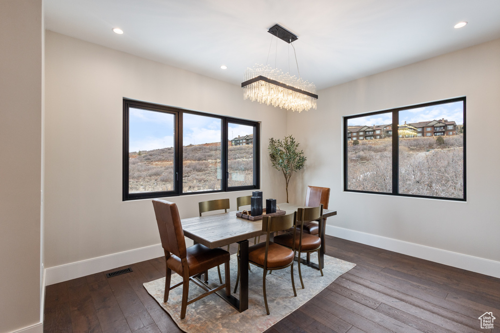 Dining area with a chandelier, healthy amount of natural light, dark wood-type flooring, and recessed lighting