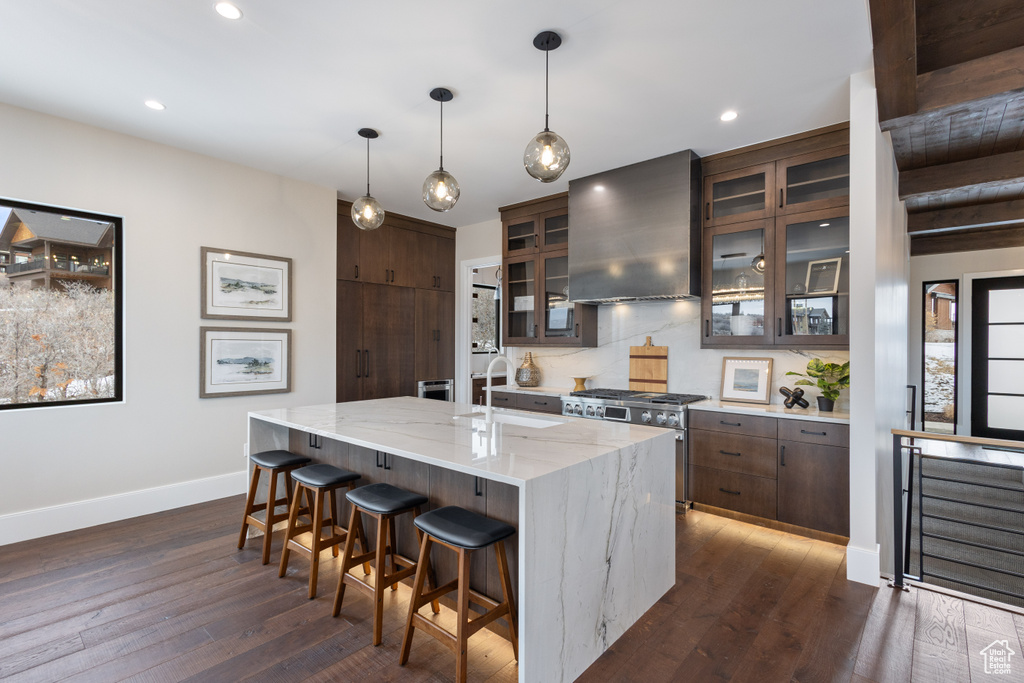 Kitchen featuring ventilation hood, high end stainless steel range, a sink, baseboards, and dark brown cabinets