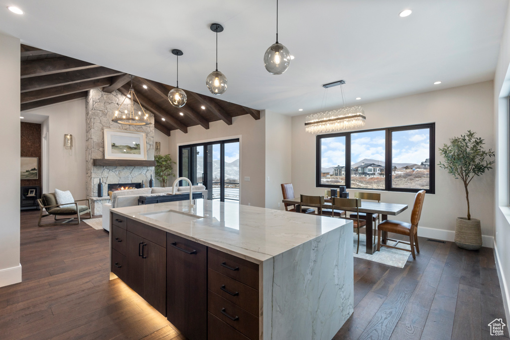 Kitchen featuring a sink, dark wood-style flooring, a stone fireplace, dark brown cabinets, and recessed lighting