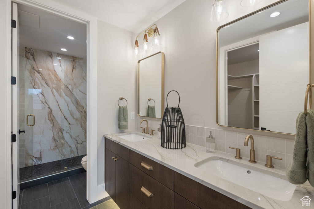 Full bathroom featuring a marble finish shower, recessed lighting, toilet, and double vanity