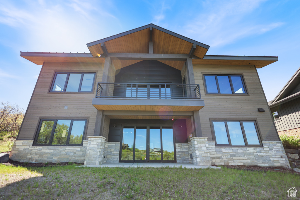 Rear view of property featuring a balcony and stone siding