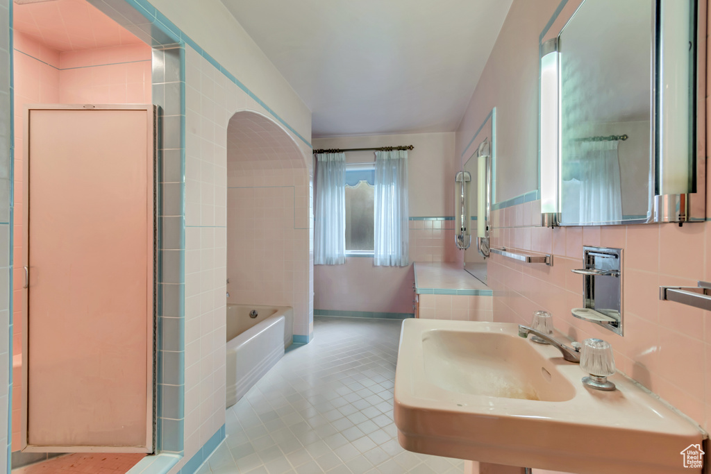 Bathroom with a bath, tile walls, tile patterned flooring, and a sink