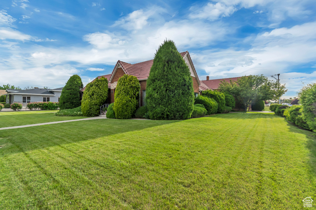 View of front of house featuring a tile roof and a front lawn